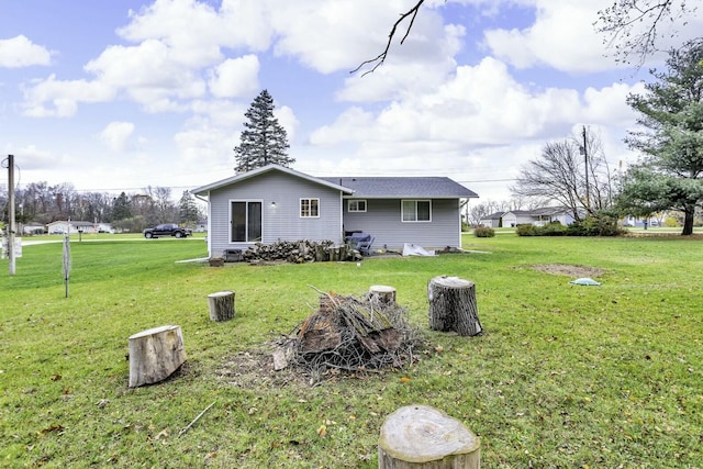 back of house featuring a shingled roof and a yard