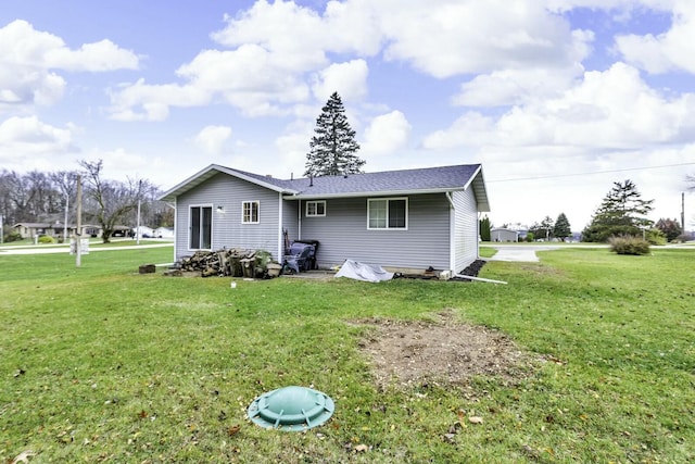 rear view of property with a lawn and a shingled roof