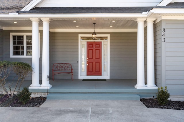 entrance to property with a shingled roof and a porch