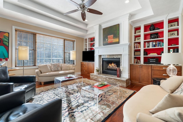 living room featuring dark wood-style floors, ceiling fan, a high end fireplace, and a raised ceiling