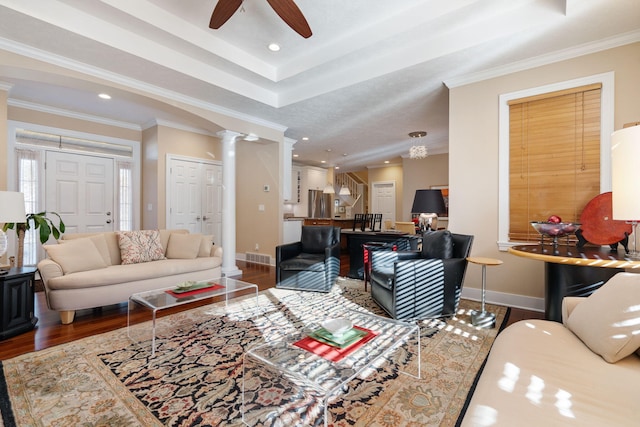 living room with decorative columns, crown molding, wood finished floors, and ceiling fan