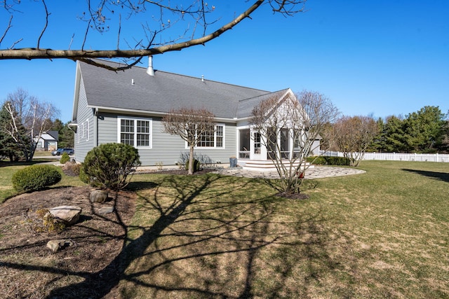rear view of house featuring a lawn, a shingled roof, fence, and a patio area