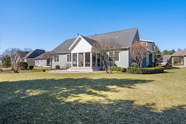 rear view of property featuring roof with shingles, a sunroom, and a yard