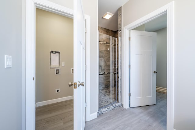 full bath with baseboards, wood finished floors, and a shower stall