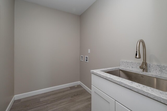 laundry room featuring light wood finished floors, a sink, baseboards, hookup for a washing machine, and cabinet space