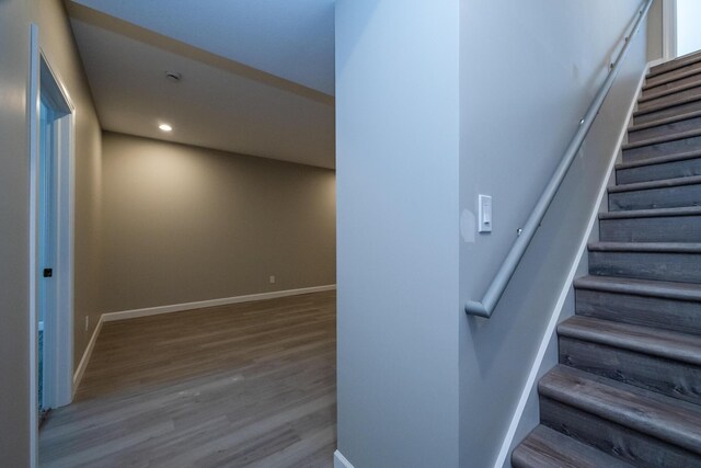stairway with baseboards, wood finished floors, and recessed lighting