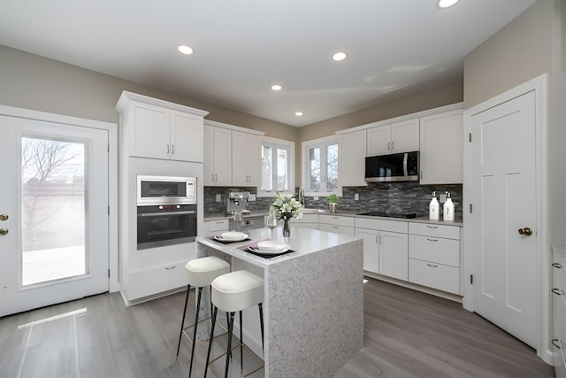 kitchen with white cabinets, a breakfast bar, appliances with stainless steel finishes, and tasteful backsplash