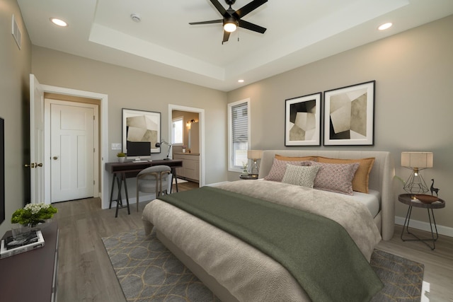 bedroom with recessed lighting, baseboards, wood finished floors, and a raised ceiling