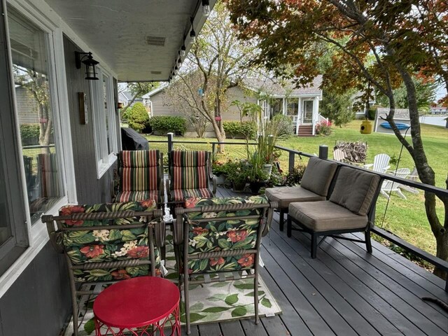 deck with an outdoor living space and a lawn