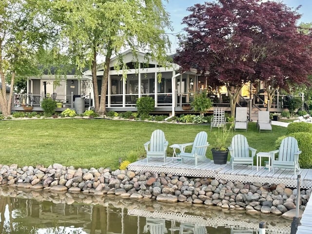back of house with a lawn, a sunroom, and a deck with water view