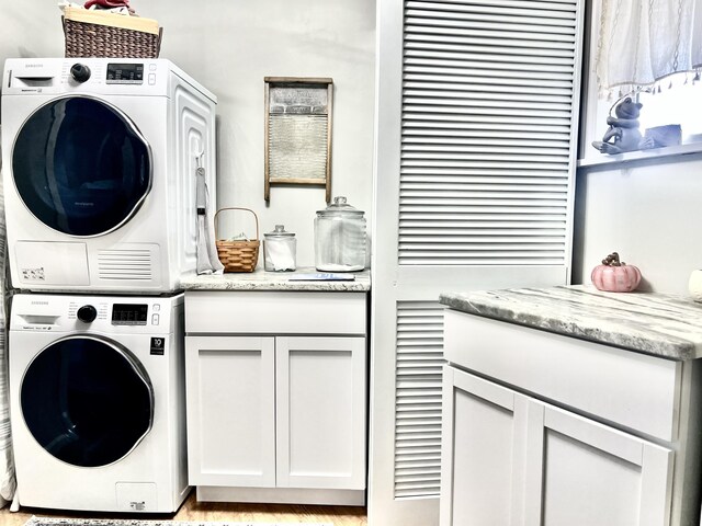 washroom featuring cabinet space and stacked washing maching and dryer