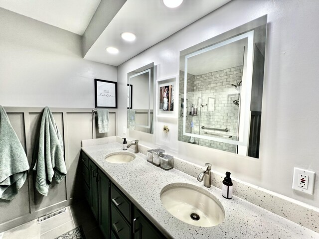 full bath featuring visible vents, a decorative wall, a sink, and tiled shower