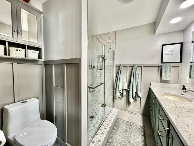 bathroom featuring vanity, a decorative wall, a shower stall, and wainscoting