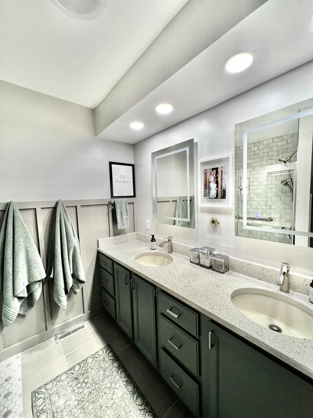 bathroom featuring double vanity, a sink, tiled shower, and visible vents