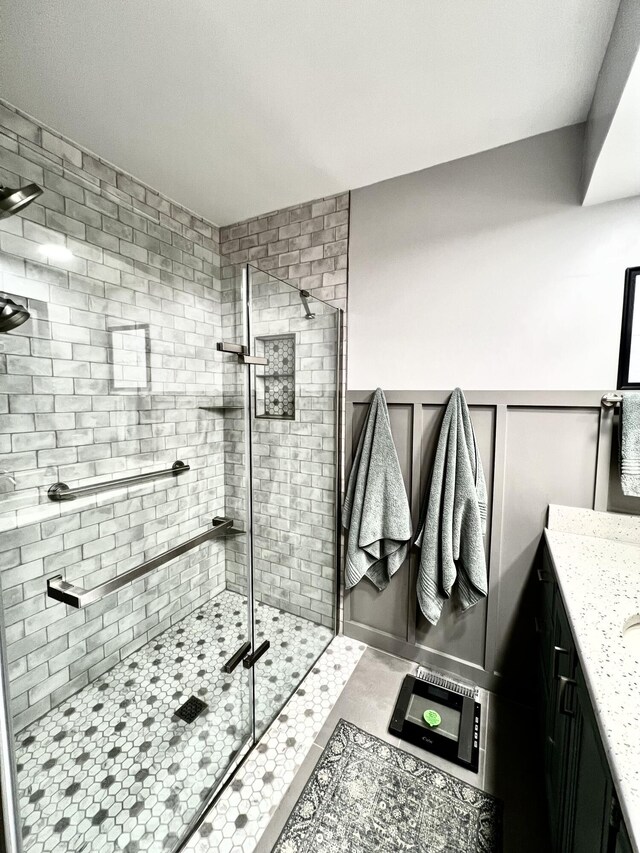 full bathroom with a decorative wall, a wainscoted wall, vanity, and a shower stall