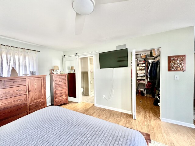 bedroom with a walk in closet, baseboards, a closet, and light wood finished floors