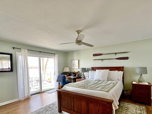 bedroom with visible vents, baseboards, access to outside, wood finished floors, and a ceiling fan