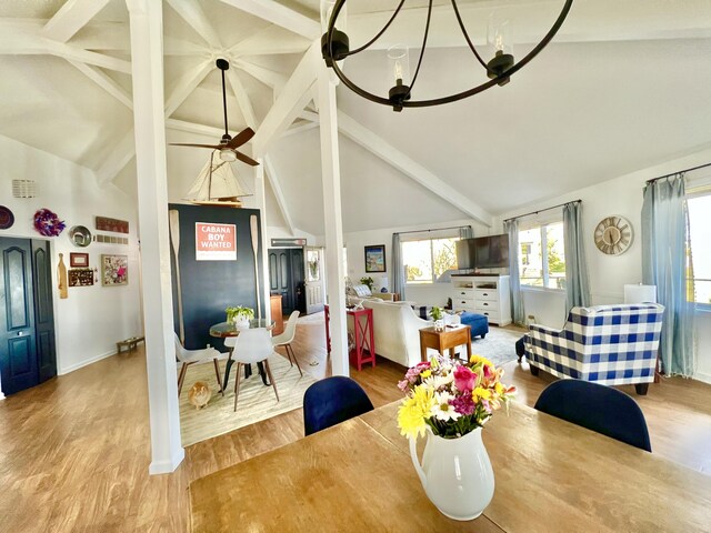 dining room with vaulted ceiling with beams, wood finished floors, and ceiling fan with notable chandelier