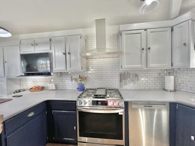 kitchen featuring light countertops, backsplash, white cabinetry, wall chimney exhaust hood, and appliances with stainless steel finishes