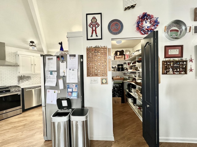 kitchen with beam ceiling, light wood finished floors, white cabinetry, stainless steel appliances, and decorative backsplash