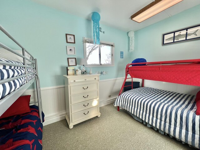 bedroom featuring a wainscoted wall and carpet floors