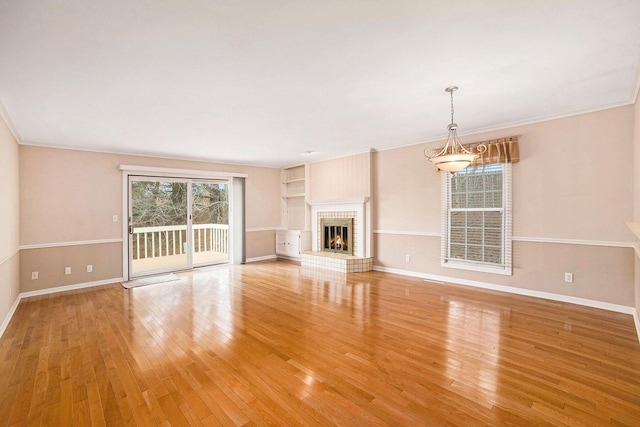 17650 Woodbridge Rd # 1, Spring Lake, MI 49456 - unfurnished living room with light wood-style floors, baseboards, ornamental molding, a warm lit fireplace, and built in shelves