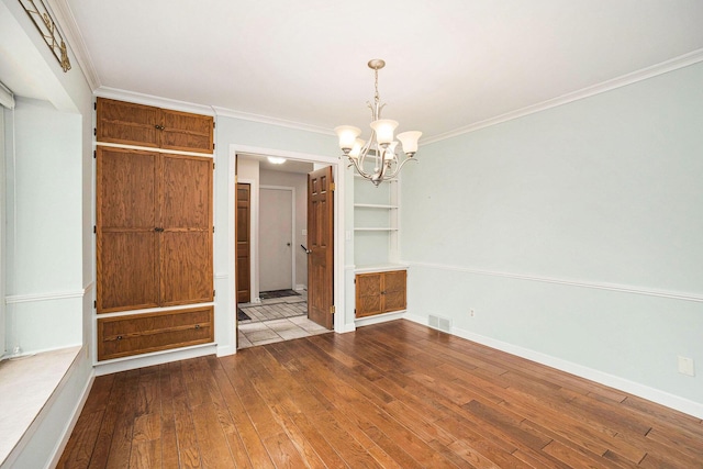 17650 Woodbridge Rd # 1, Spring Lake, MI 49456 - empty room featuring a chandelier, dark wood-style flooring, crown molding, and baseboards