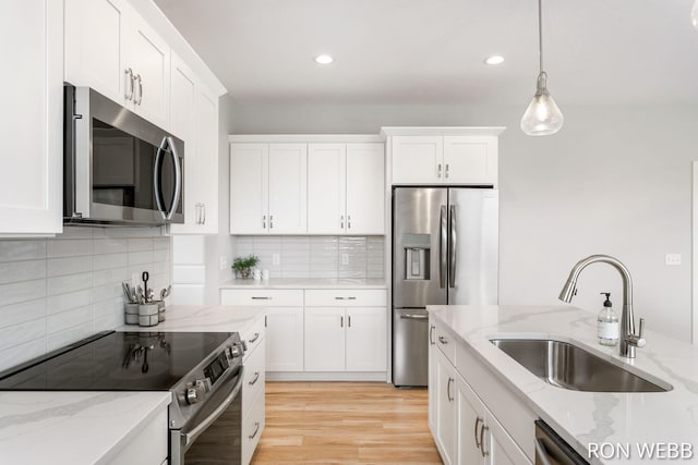 kitchen featuring white cabinetry, a sink, stainless steel appliances, and pendant lighting