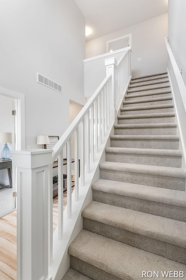 stairway with visible vents and a towering ceiling