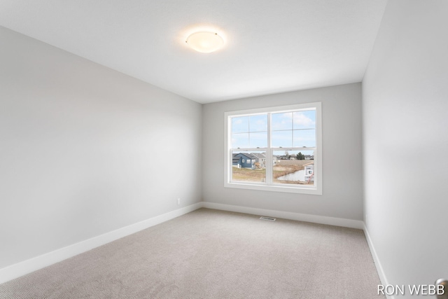unfurnished room with baseboards, visible vents, and light colored carpet