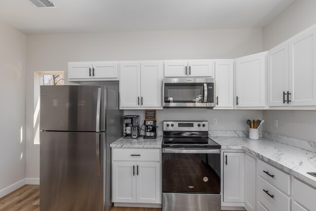 2084 W Fenwick Rd, Fenwick, MI 48834 - kitchen featuring white cabinetry, stainless steel appliances, baseboards, and light wood-style floors