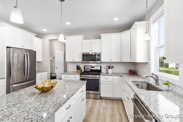 kitchen with appliances with stainless steel finishes, a sink, white cabinetry, decorative backsplash, and recessed lighting