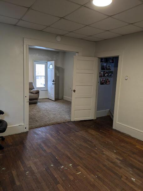 711 Randolph St, Jackson, MI 49203 - empty room with hardwood / wood-style floors, baseboards, and a paneled ceiling