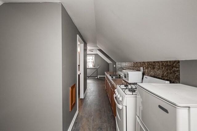 7295 Dutch Rd, Goodrich Vlg, MI 48438 - kitchen with white appliances, baseboards, dark wood-type flooring, a sink, and vaulted ceiling