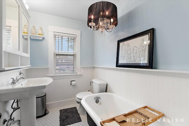 548 Pleasant St SE, Grand Rapids, MI 49503 - bathroom featuring a freestanding tub, a wainscoted wall, and a chandelier