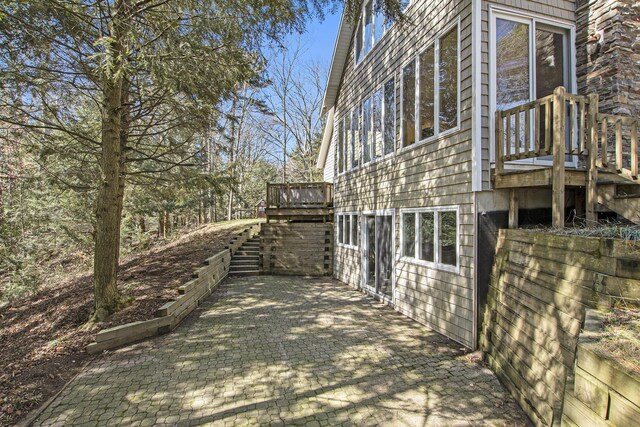 view of side of home with a wooden deck and a patio area