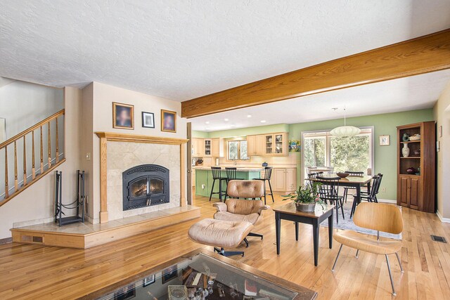 living area with a fireplace, light wood-style floors, stairway, and a textured ceiling