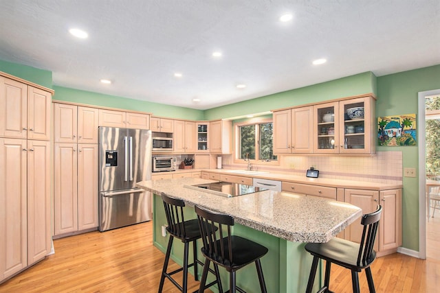 kitchen with a kitchen island, a kitchen breakfast bar, a sink, and stainless steel appliances