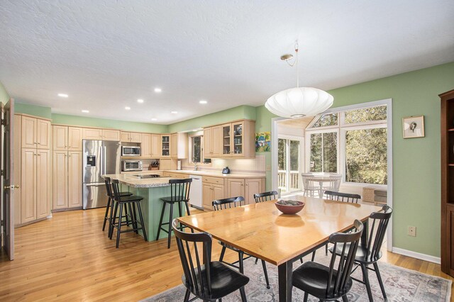 dining space featuring baseboards, light wood-style floors, a textured ceiling, and recessed lighting