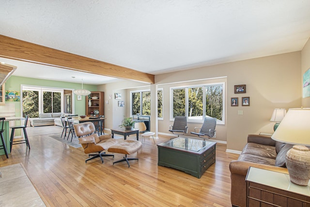 living room featuring baseboards, light wood-type flooring, and beamed ceiling