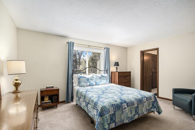 bedroom featuring light colored carpet, baseboards, and a textured ceiling
