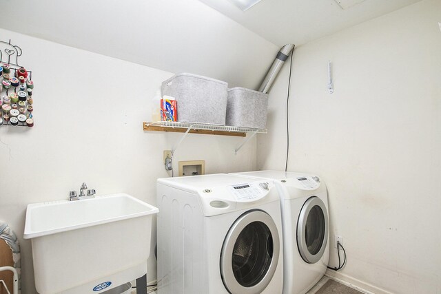 washroom with baseboards, washing machine and dryer, a sink, and laundry area