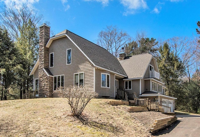 view of property exterior featuring a chimney, a garage, and roof with shingles