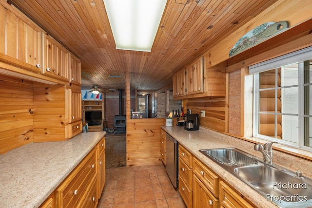 kitchen featuring light countertops, dishwasher, a sink, a wood stove, and wood ceiling