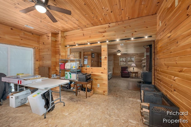 office area with a ceiling fan, wood walls, and a wood stove