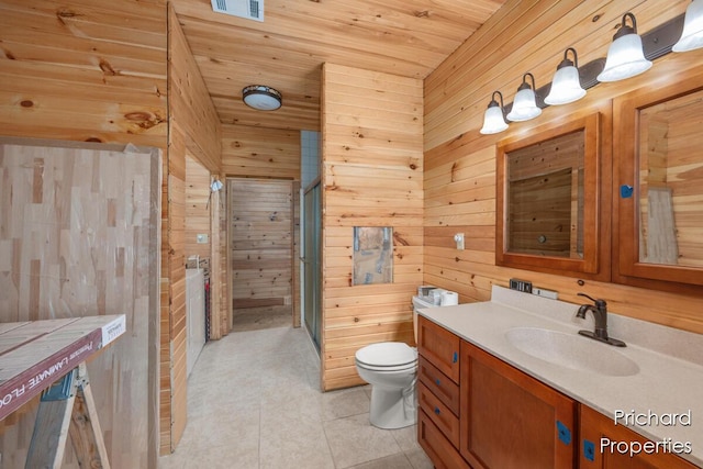 bathroom featuring vanity, wood walls, toilet, a shower stall, and tile patterned floors