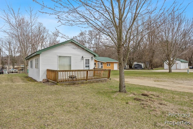 exterior space with driveway, an outdoor structure, a lawn, and a wooden deck