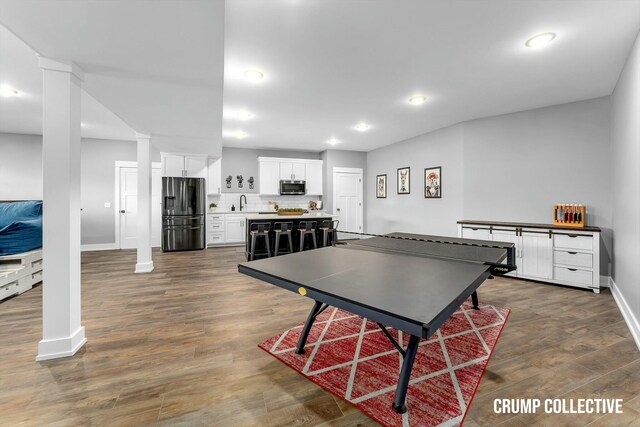 playroom featuring decorative columns, a sink, dark wood-style floors, baseboards, and recessed lighting