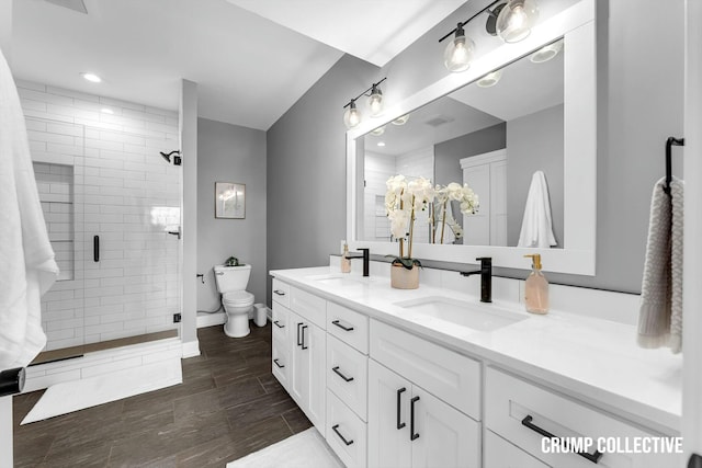 full bathroom with toilet, a sink, double vanity, and a shower stall