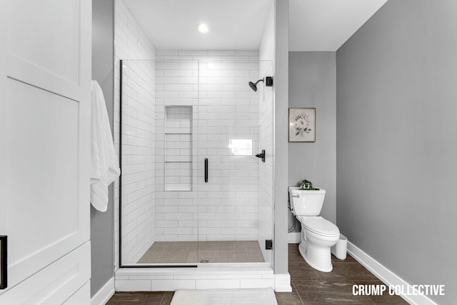 bathroom with toilet, wood finished floors, baseboards, and a shower stall